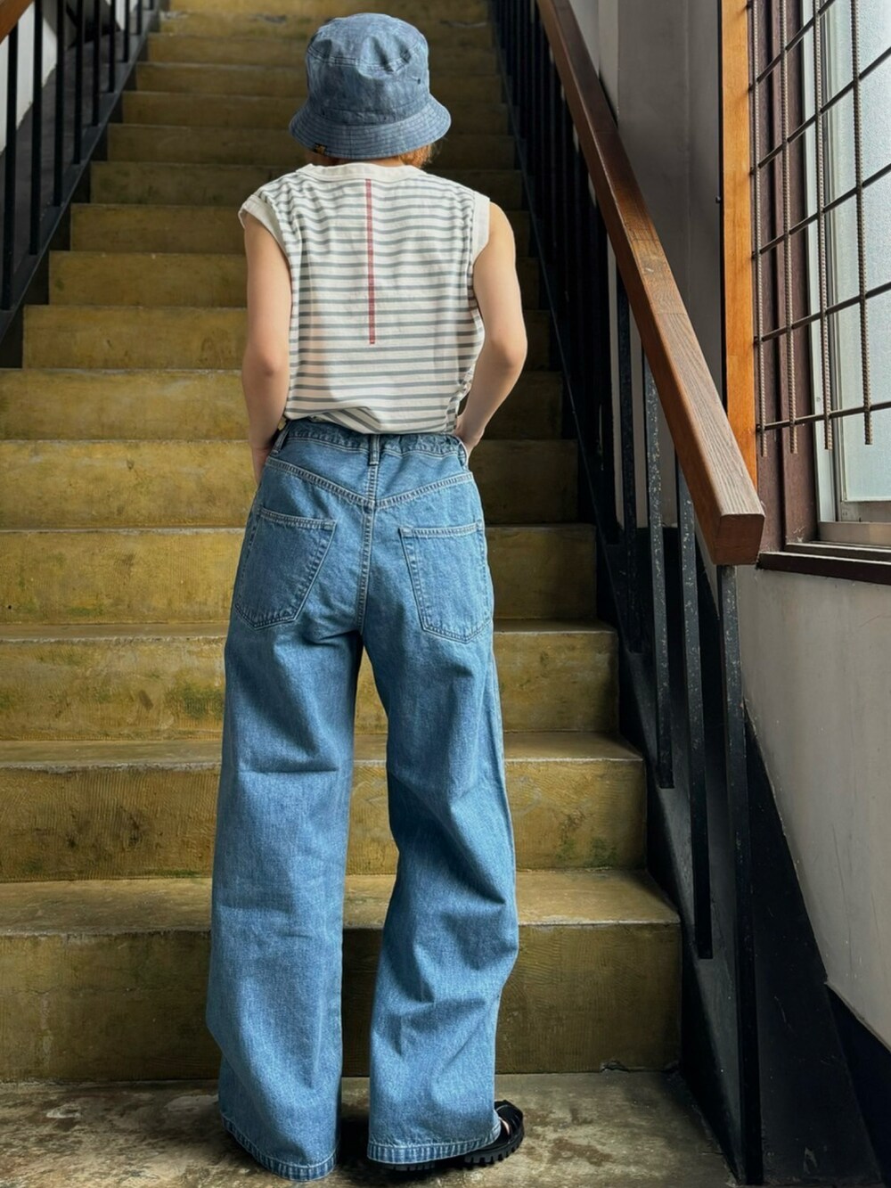 グレー系のタンクトップ、ブルー系のデニムパンツ、ブラック系のシューズを着用したレディースの冬コーディネートの2枚目の写真