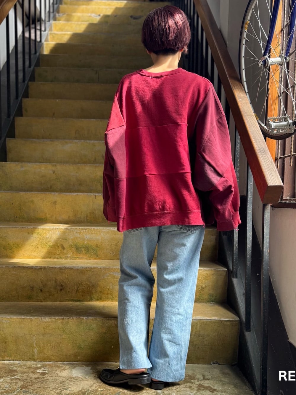 レッド系のスウェット、ブルー系のパンツを着用したレディースの秋コーディネートの2枚目の写真