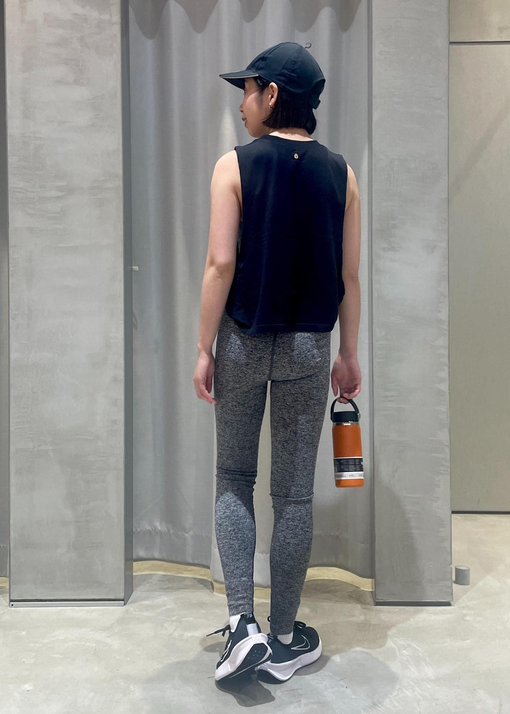 ブラック系のタンクトップ、ブラック系のスニーカー、ブラック系のキャップを着用したレディースの冬コーディネートの4枚目の写真