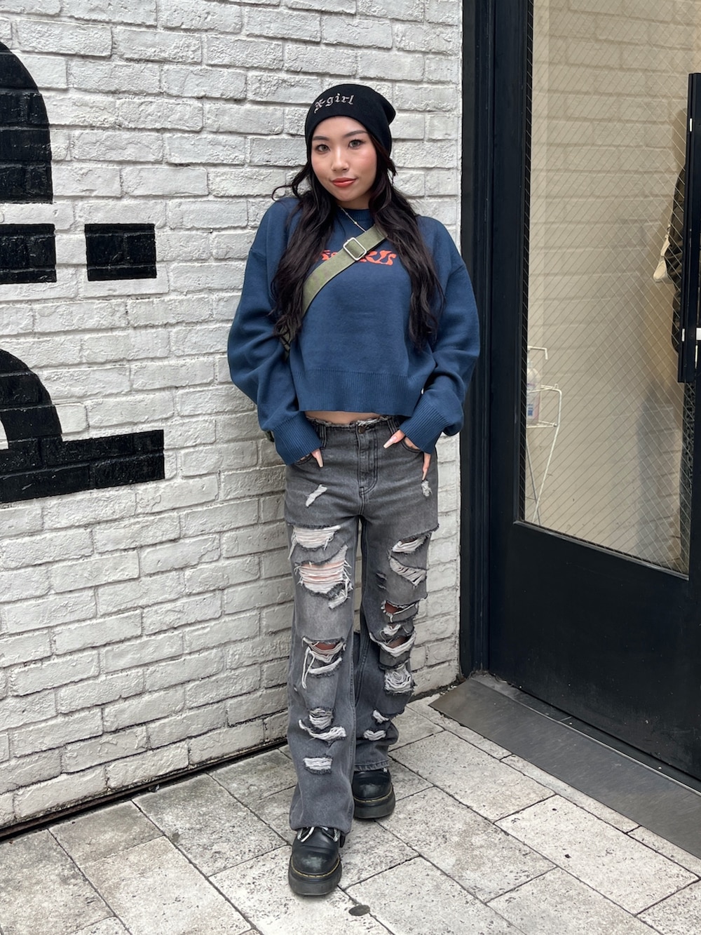 ブルー系のニット/セーター、ブラック系のデニムパンツ、グリーン系のショルダーバッグを着用したレディースの秋コーディネートの2枚目の写真