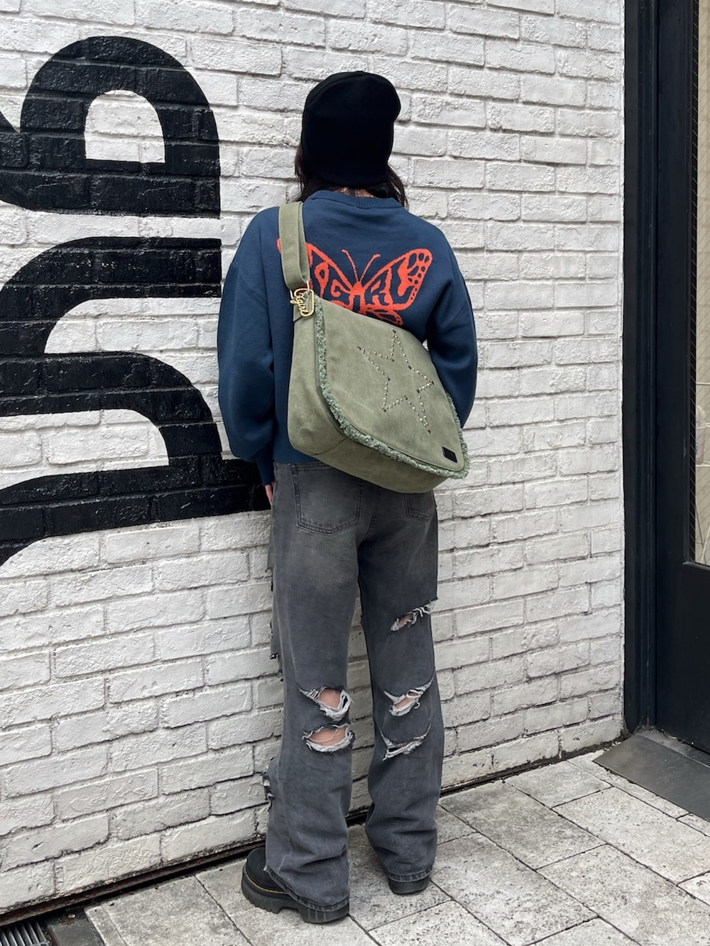 ブルー系のニット/セーター、ブラック系のデニムパンツ、グリーン系のショルダーバッグを着用したレディースの秋コーディネートの3枚目の写真