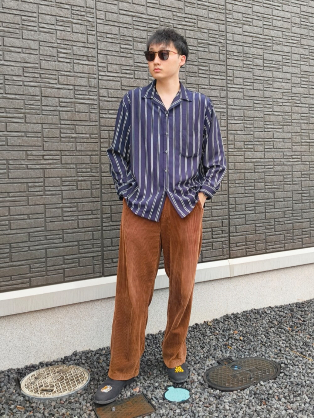 ブラック系のスリッポン、ブラウン系のその他パンツ、ブルー系のシャツ/ブラウスを着用したメンズの夏コーディネートの2枚目の写真