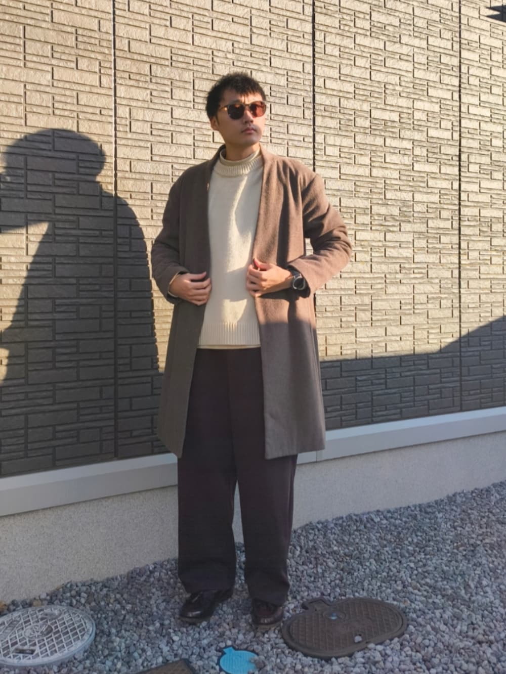 その他のスウェットパンツ、ブラウン系のローファー、ブラウン系のノーカラーコートを着用したメンズの冬コーディネートの2枚目の写真