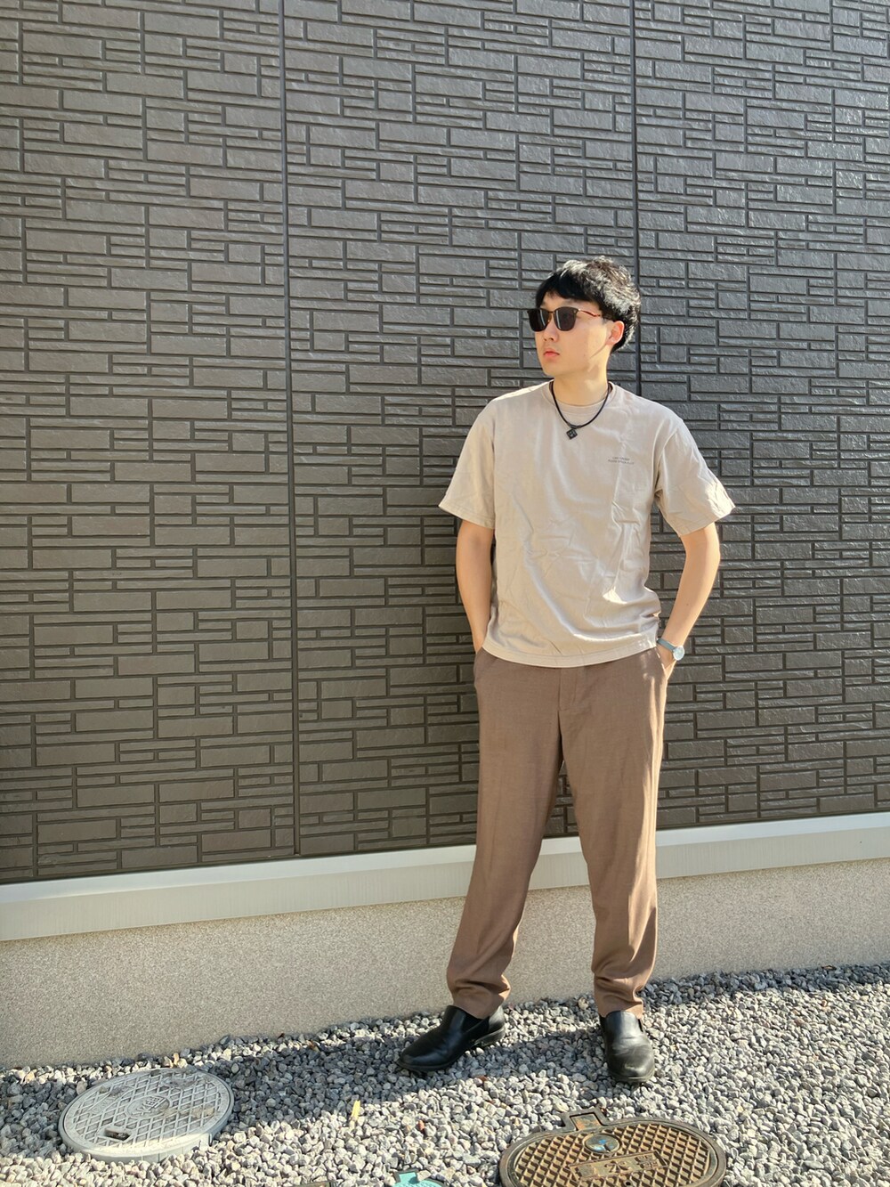 ブラック系のドレスシューズ、ブラウン系のスラックス、ベージュ系のTシャツ/カットソーを着用したメンズの夏コーディネートの2枚目の写真