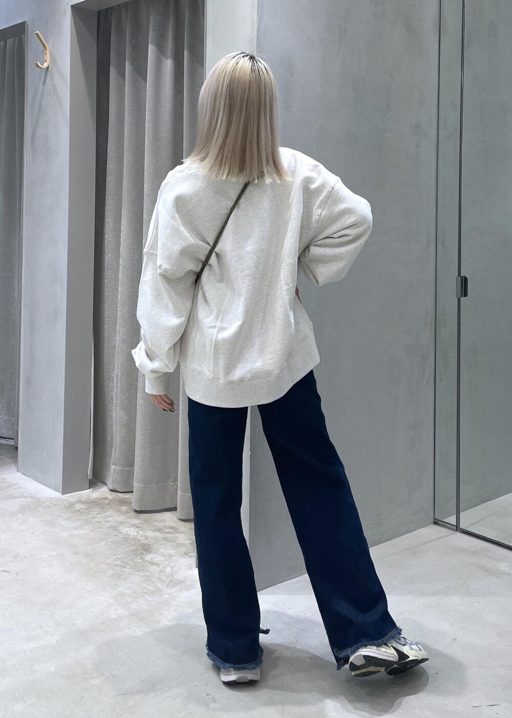 ブルー系のデニムパンツ、ホワイト系のスニーカー、ホワイト系のスウェットを着用したレディースの冬コーディネートの4枚目の写真