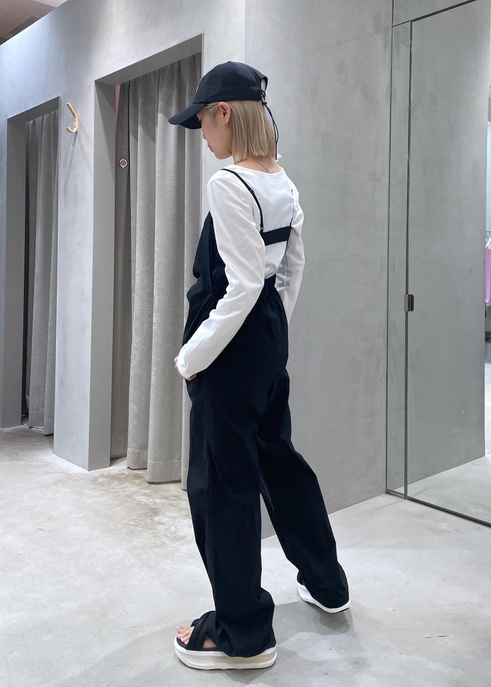 ブラック系のサンダル、ホワイト系のTシャツ/カットソー、ブラック系のサロペット/オーバーオールを着用したレディースの夏コーディネートの2枚目の写真