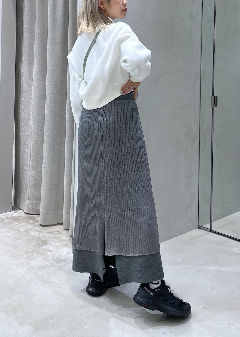 ブラック系のスニーカー、グレー系のスカート、グリーン系のショルダーバッグを着用したレディースの秋コーディネートの4枚目の写真