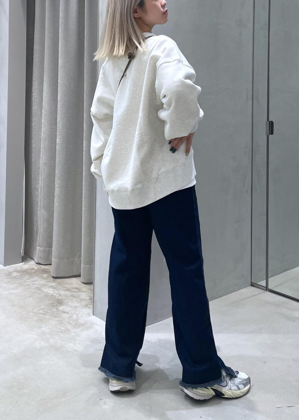 ブルー系のデニムパンツ、ホワイト系のスニーカー、ホワイト系のスウェットを着用したレディースの冬コーディネートの3枚目の写真