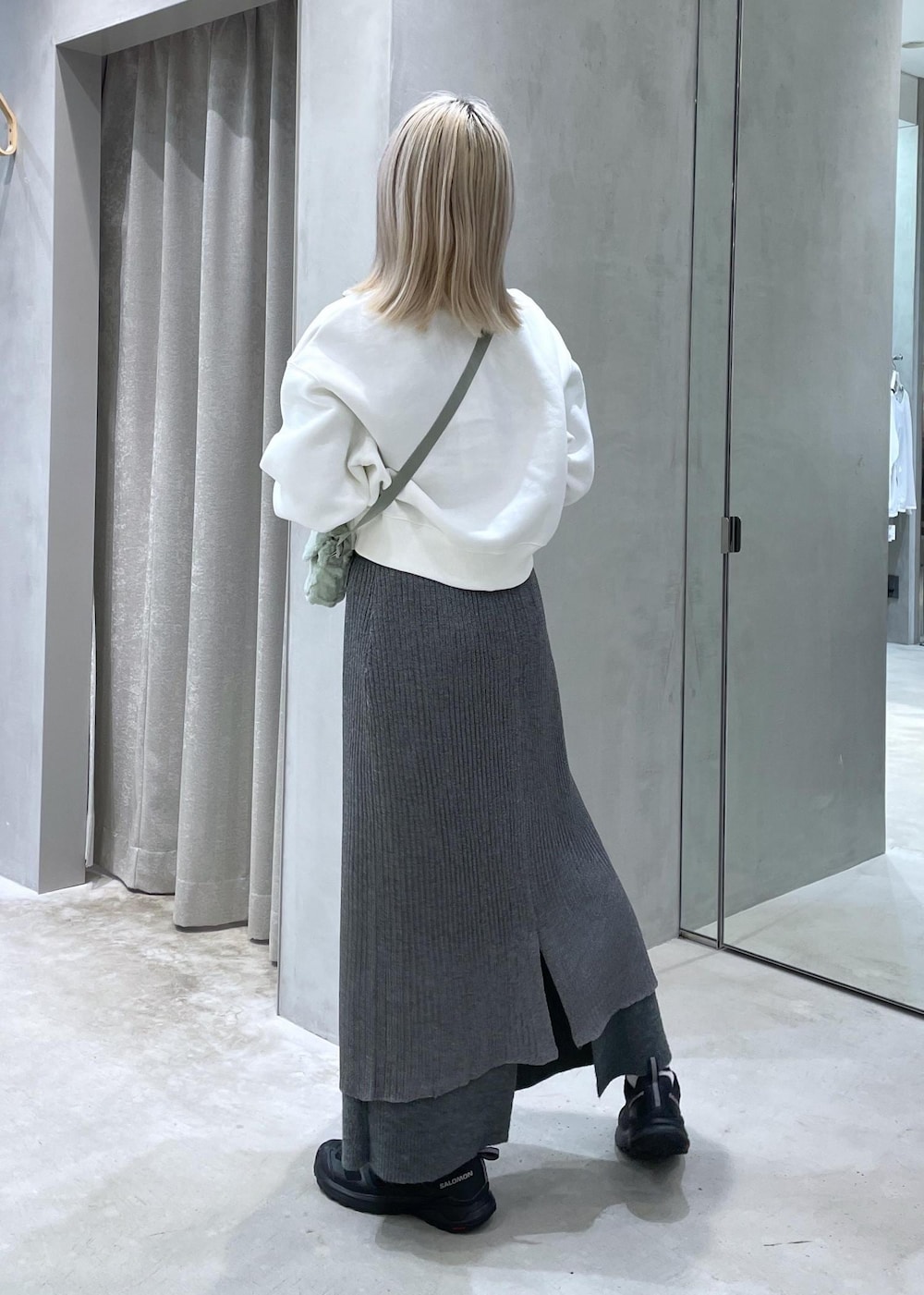 ブラック系のスニーカー、グレー系のスカート、グリーン系のショルダーバッグを着用したレディースの秋コーディネートの3枚目の写真