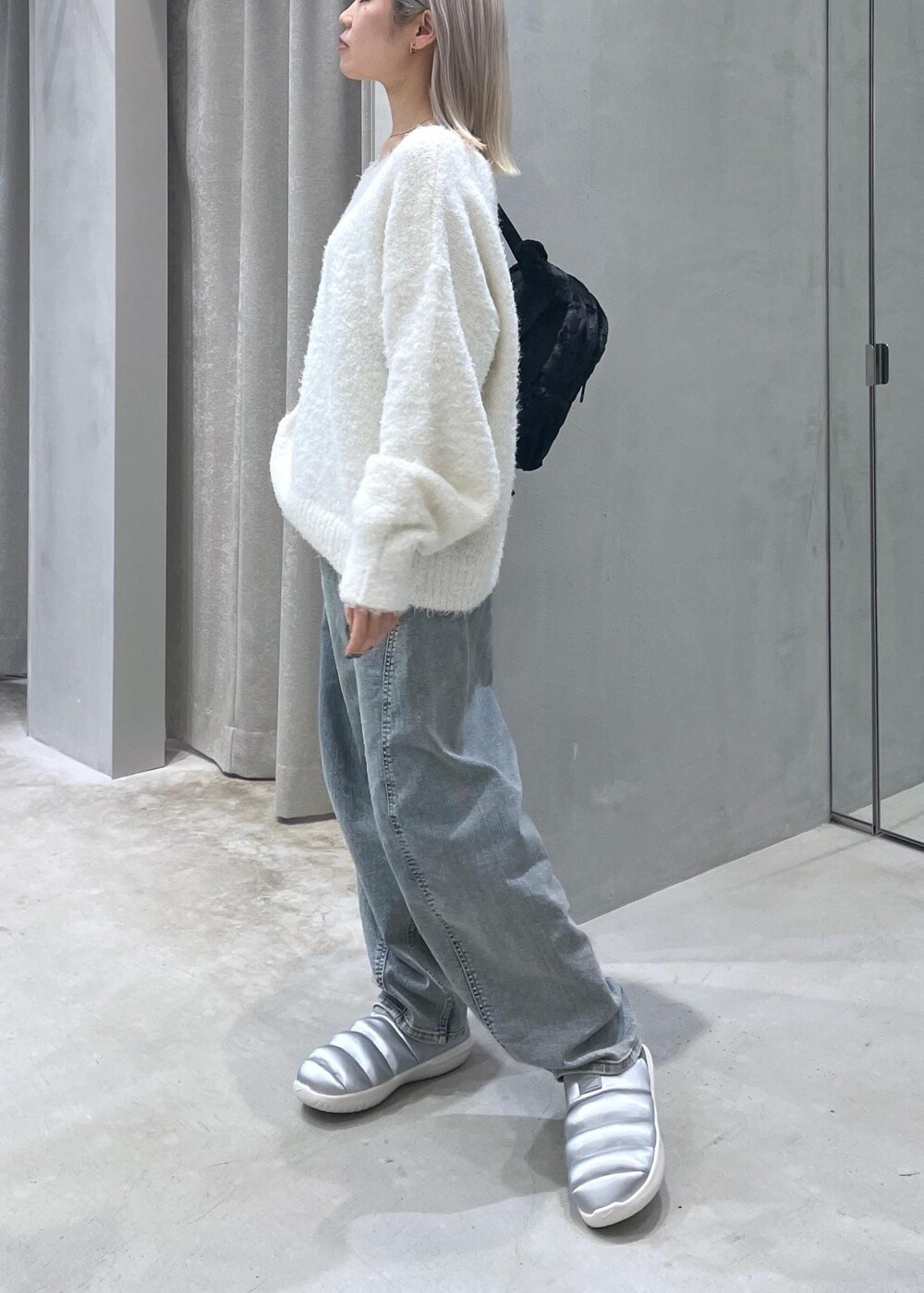 ホワイト系のニット/セーター、ベージュ系のデニムパンツ、シルバー系のスリッポンを着用したレディースの冬コーディネートの2枚目の写真