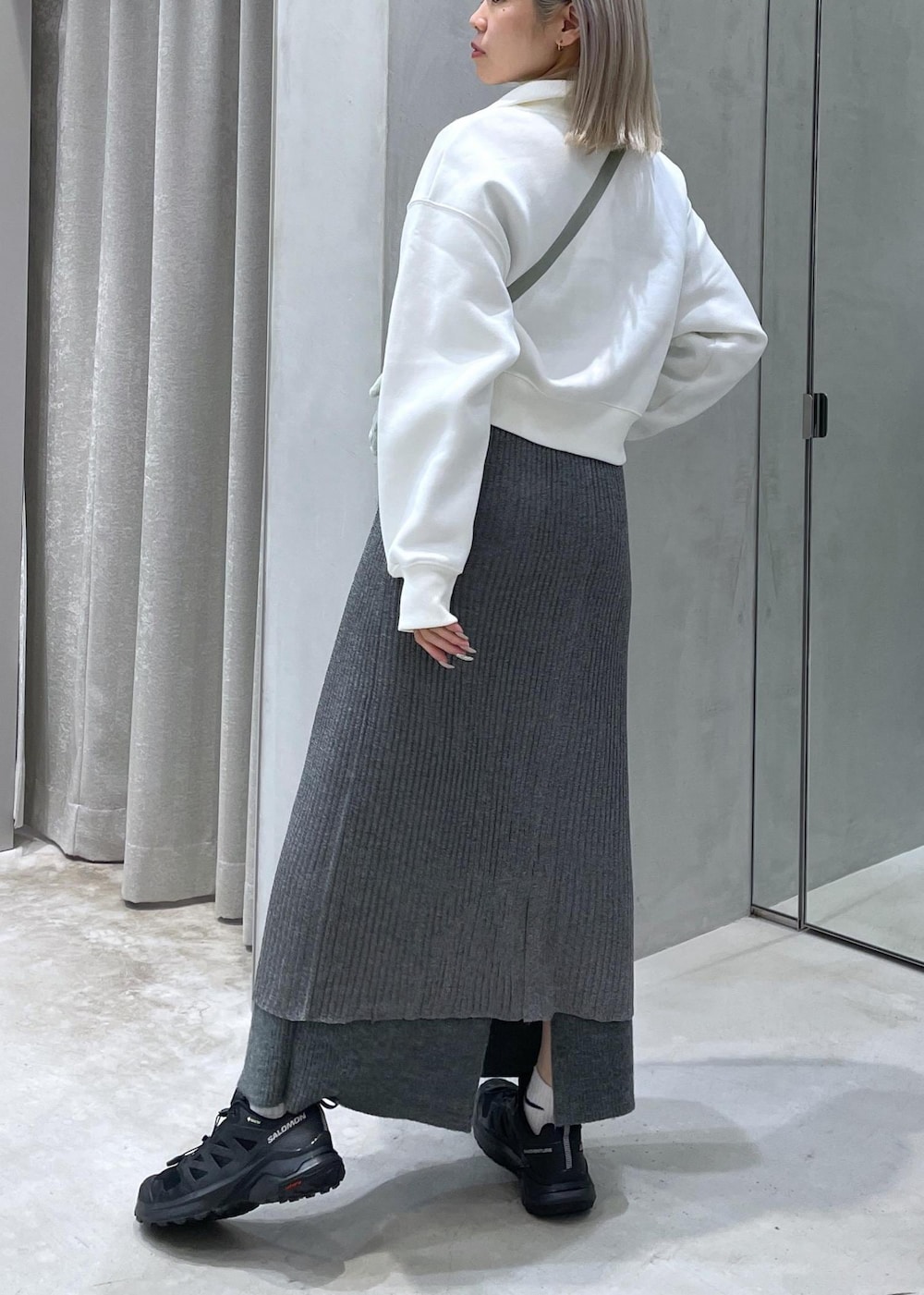 ブラック系のスニーカー、グレー系のスカート、グリーン系のショルダーバッグを着用したレディースの秋コーディネートの2枚目の写真