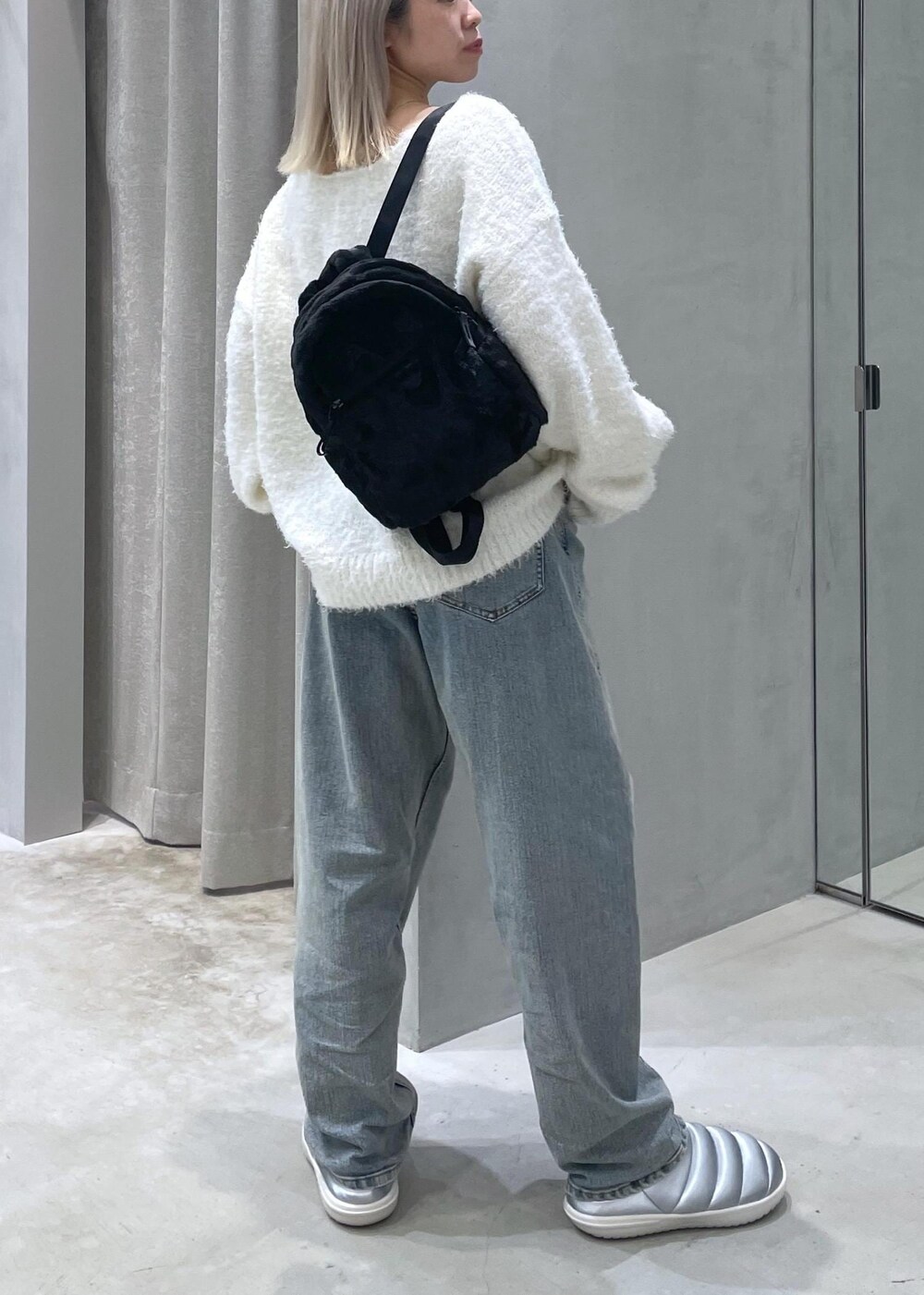 ホワイト系のニット/セーター、ベージュ系のデニムパンツ、シルバー系のスリッポンを着用したレディースの冬コーディネートの4枚目の写真