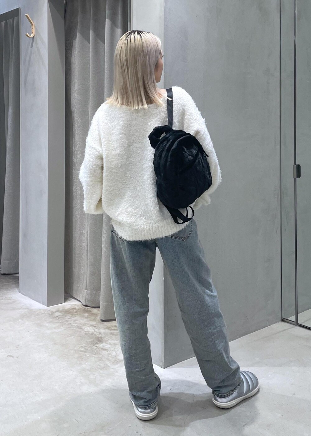 ホワイト系のニット/セーター、ベージュ系のデニムパンツ、シルバー系のスリッポンを着用したレディースの冬コーディネートの3枚目の写真
