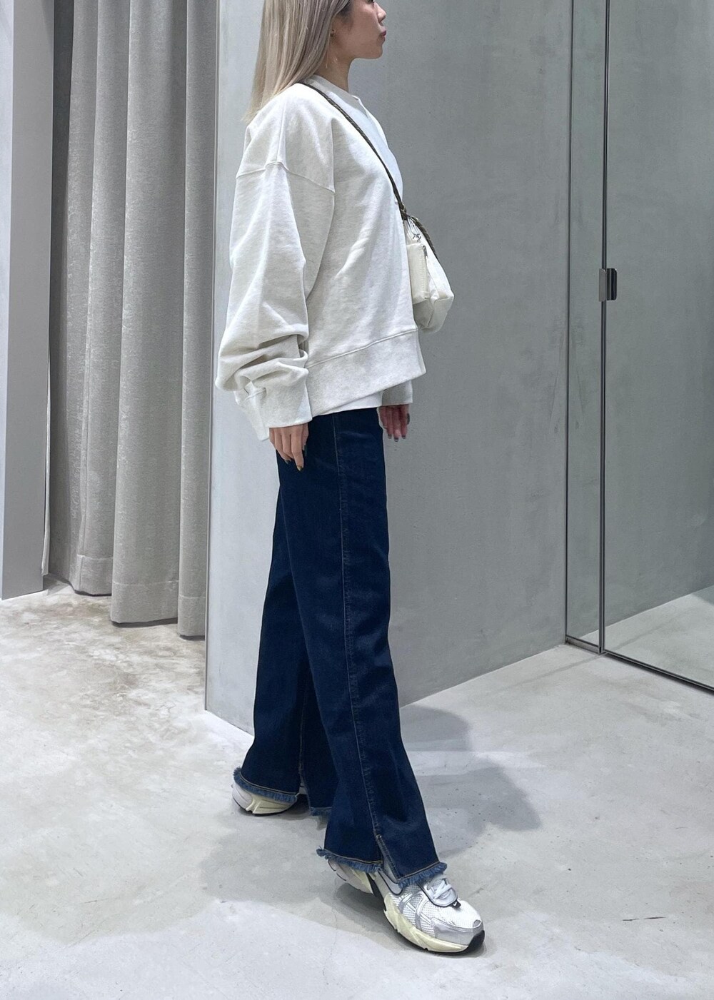ブルー系のデニムパンツ、ホワイト系のスニーカー、ホワイト系のスウェットを着用したレディースの冬コーディネートの2枚目の写真