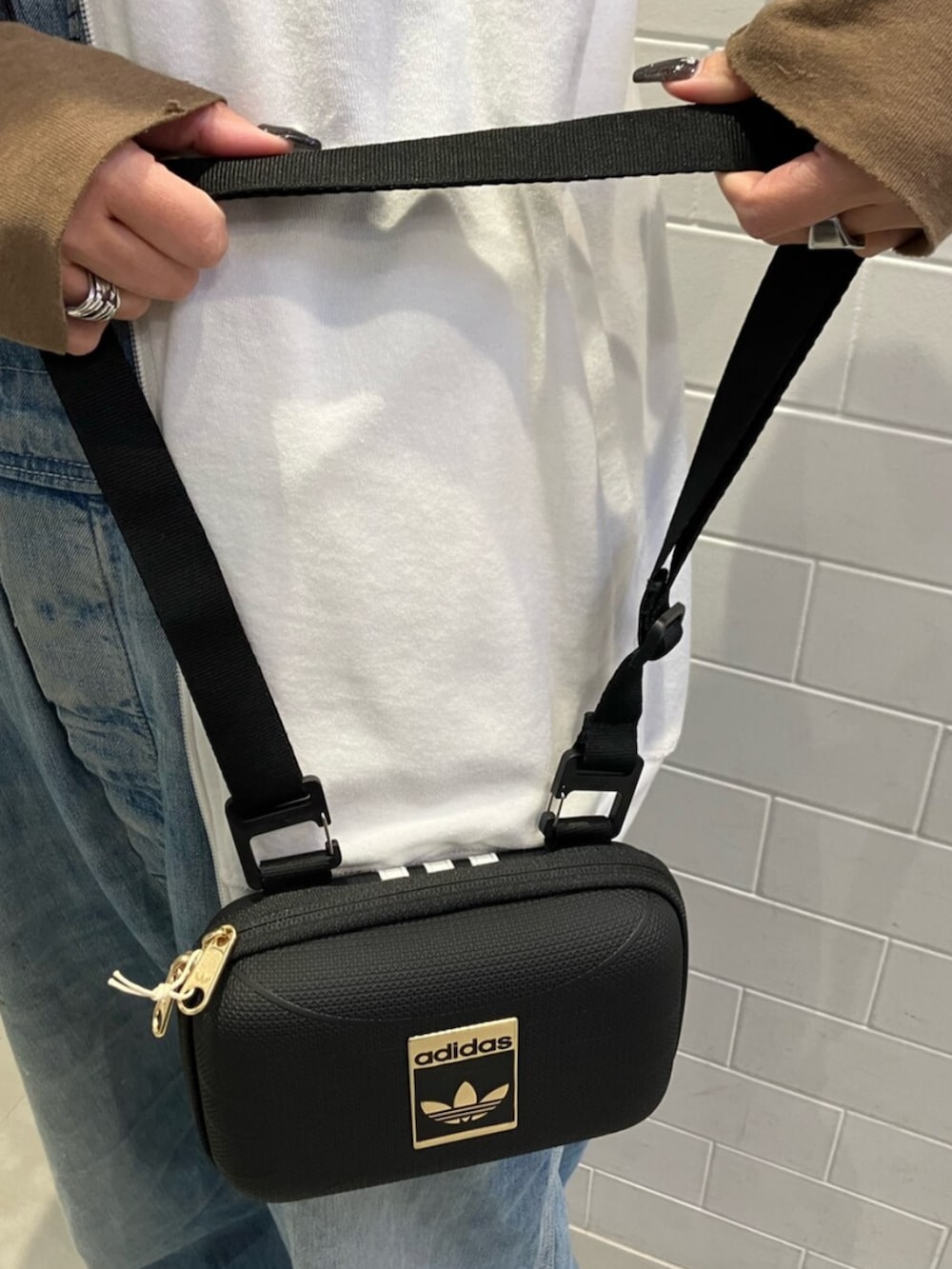 ホワイト系のジャージ、ブラック系のショルダーバッグ、ブラック系のスニーカーを着用したレディースの春コーディネートの3枚目の写真