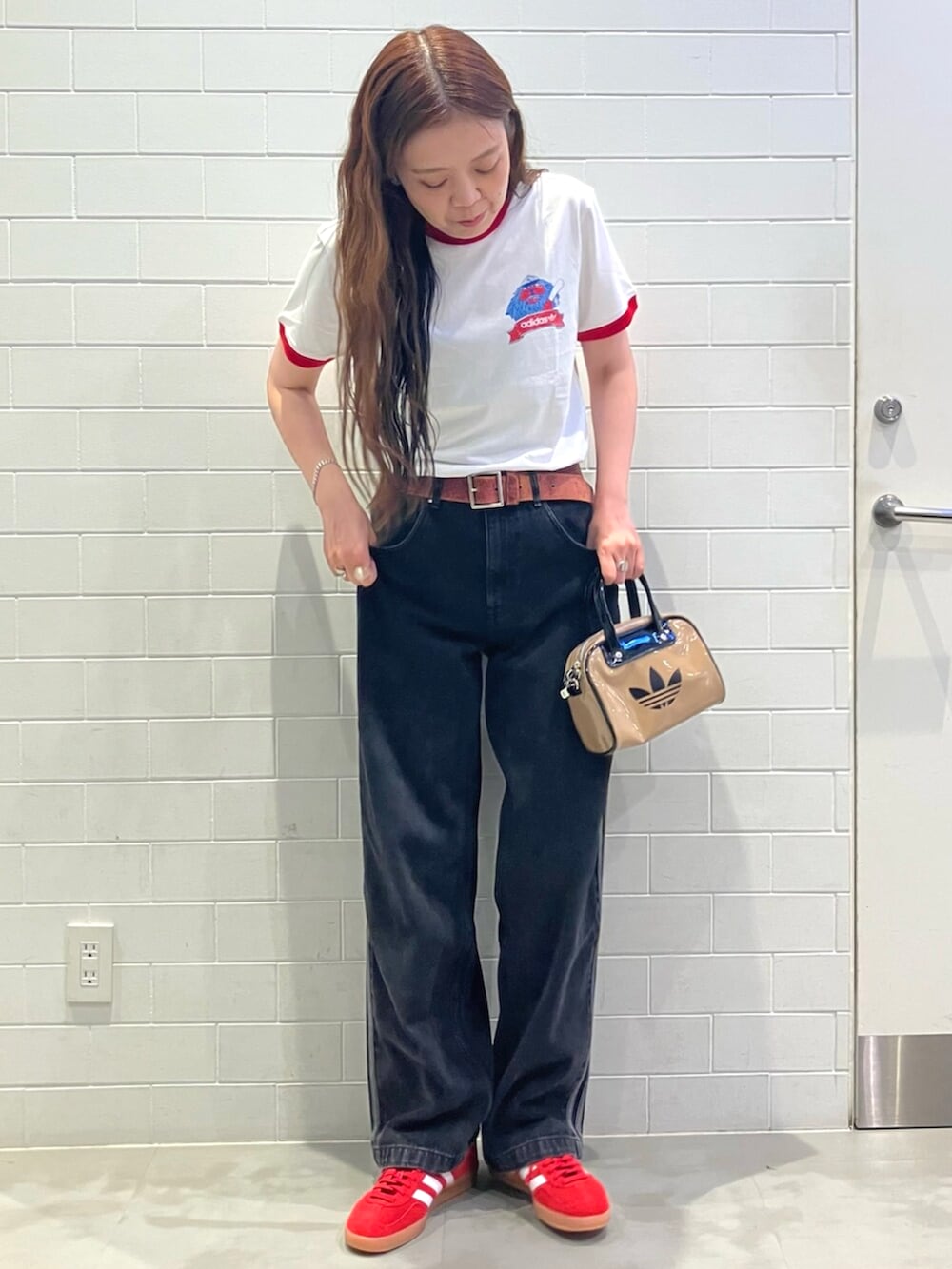 ホワイト系のトップス、ブラック系のデニムパンツ、ベージュ系のショルダーバッグを着用したレディースの夏コーディネートの2枚目の写真