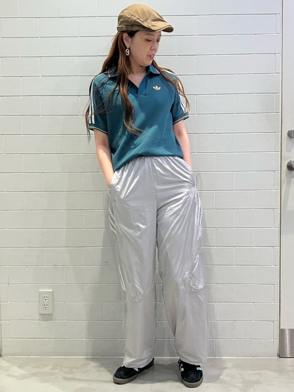 グリーン系のポロシャツ、グレー系のその他パンツ、ブラック系のスニーカーを着用したレディースの夏コーディネートの2枚目の写真