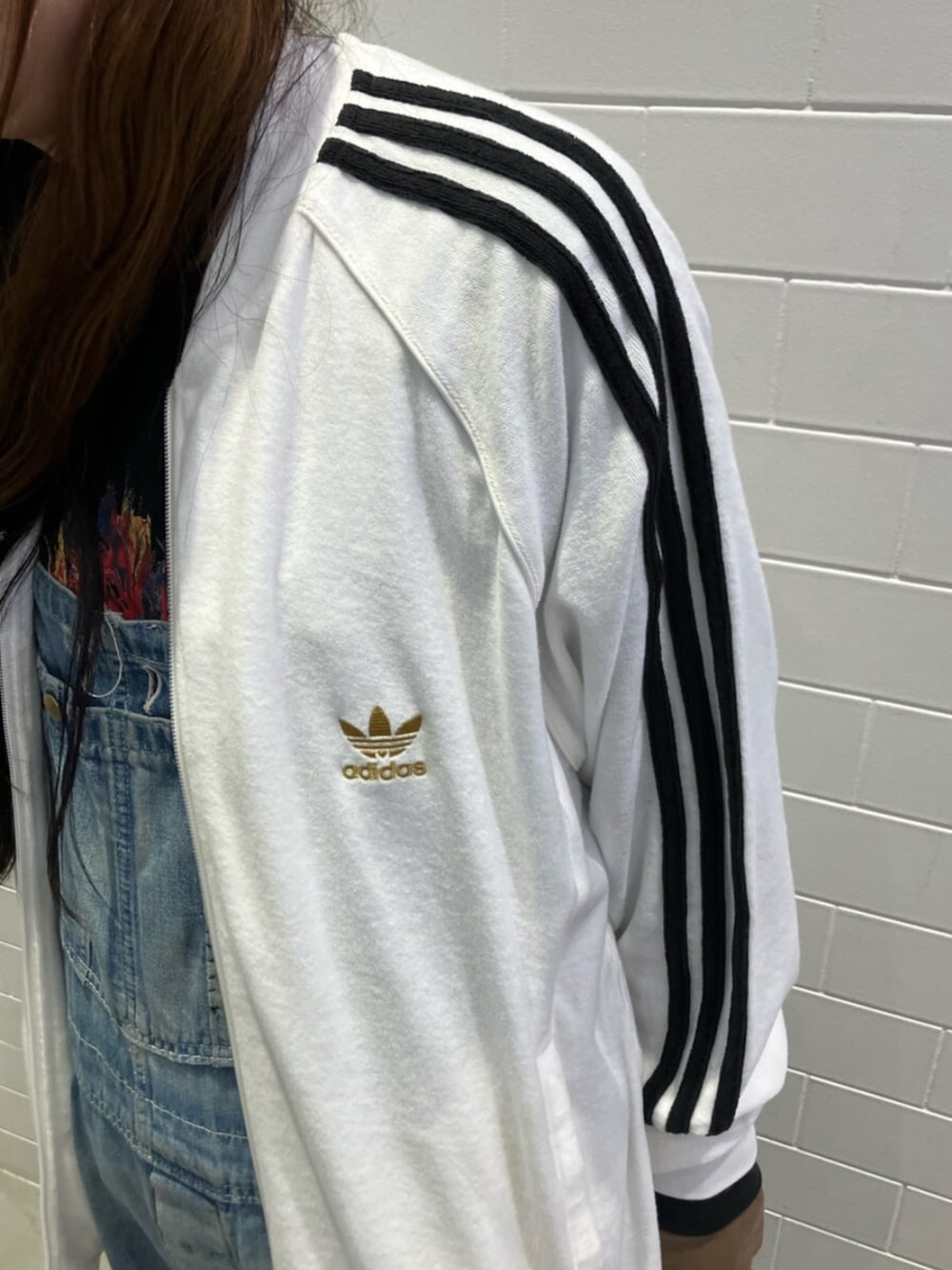 ホワイト系のジャージ、ブラック系のショルダーバッグ、ブラック系のスニーカーを着用したレディースの春コーディネートの2枚目の写真