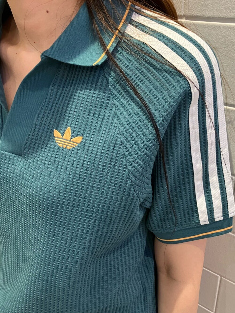 グリーン系のポロシャツ、グレー系のその他パンツ、ブラック系のスニーカーを着用したレディースの夏コーディネートの4枚目の写真