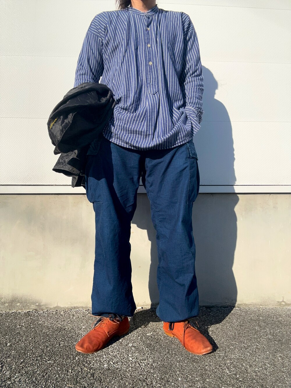 ブルー系のカーゴパンツ、ブラウン系のドレスシューズ、ブラック系のジャケット/アウターを着用したメンズの冬コーディネートの2枚目の写真