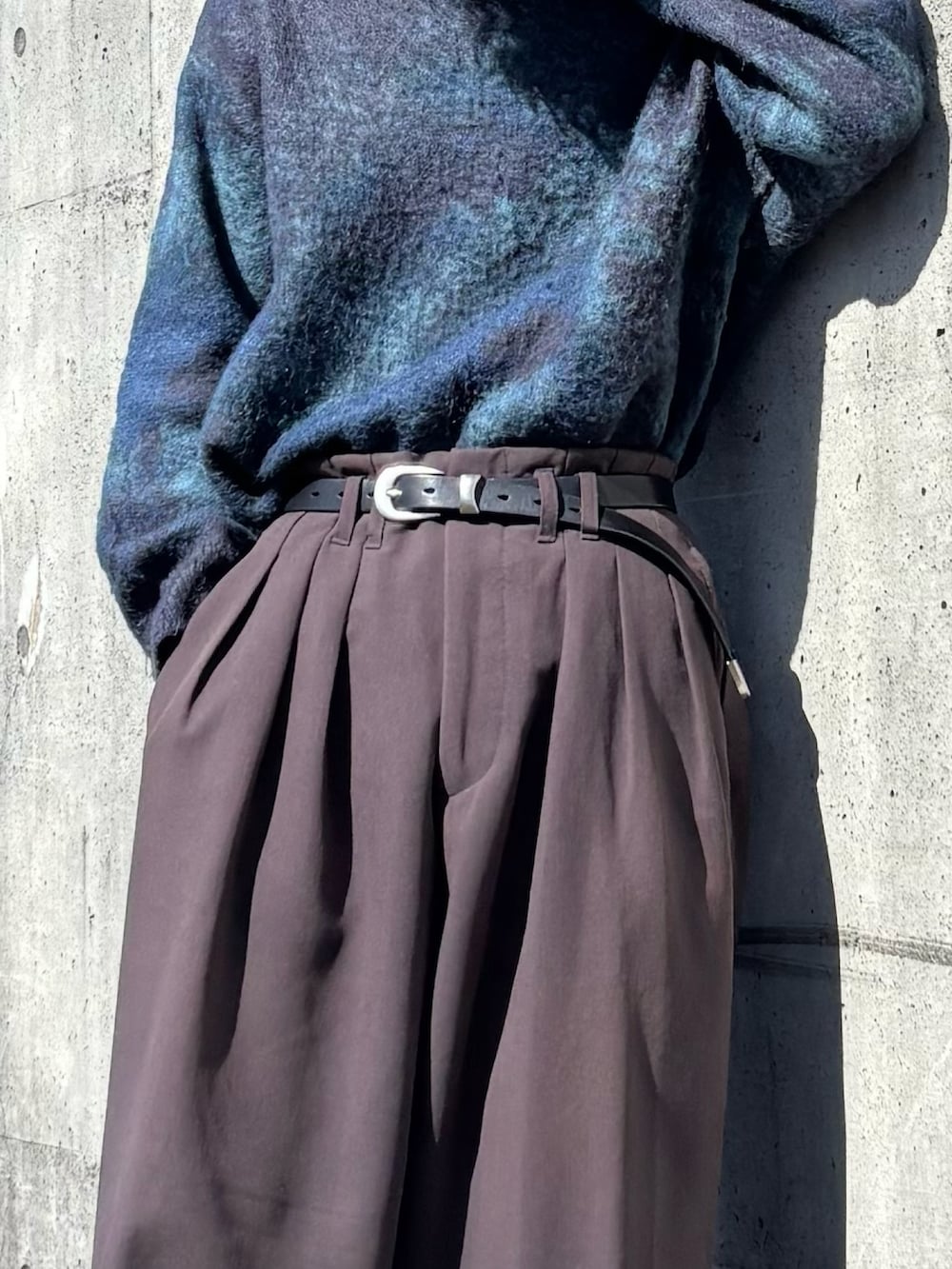 ブルー系のニット/セーター、ブラウン系のスラックス、ブラック系のスニーカーを着用したメンズの春コーディネートの2枚目の写真