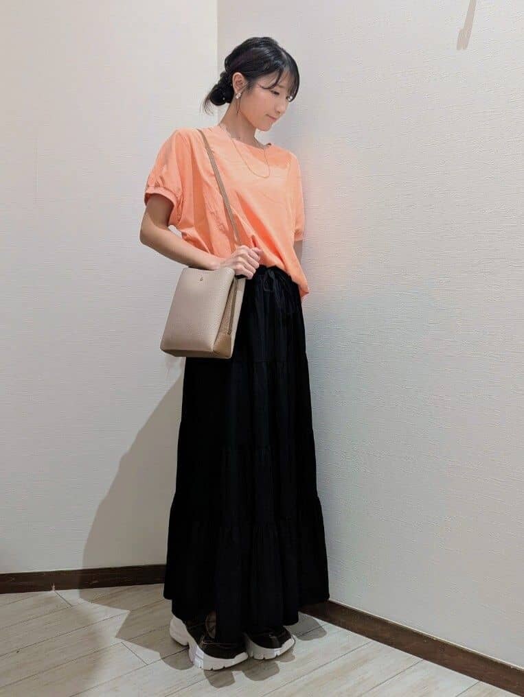 オレンジ系のシャツ/ブラウス、ブラック系のスカート、ブラウン系のスニーカーを着用したレディースの夏コーディネートの2枚目の写真