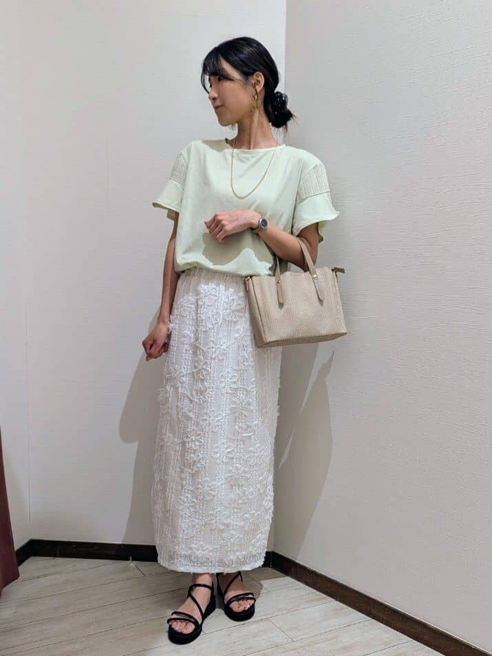 グリーン系のTシャツ/カットソー、ホワイト系のスカート、ブラック系のサンダルを着用したレディースの夏コーディネートの2枚目の写真