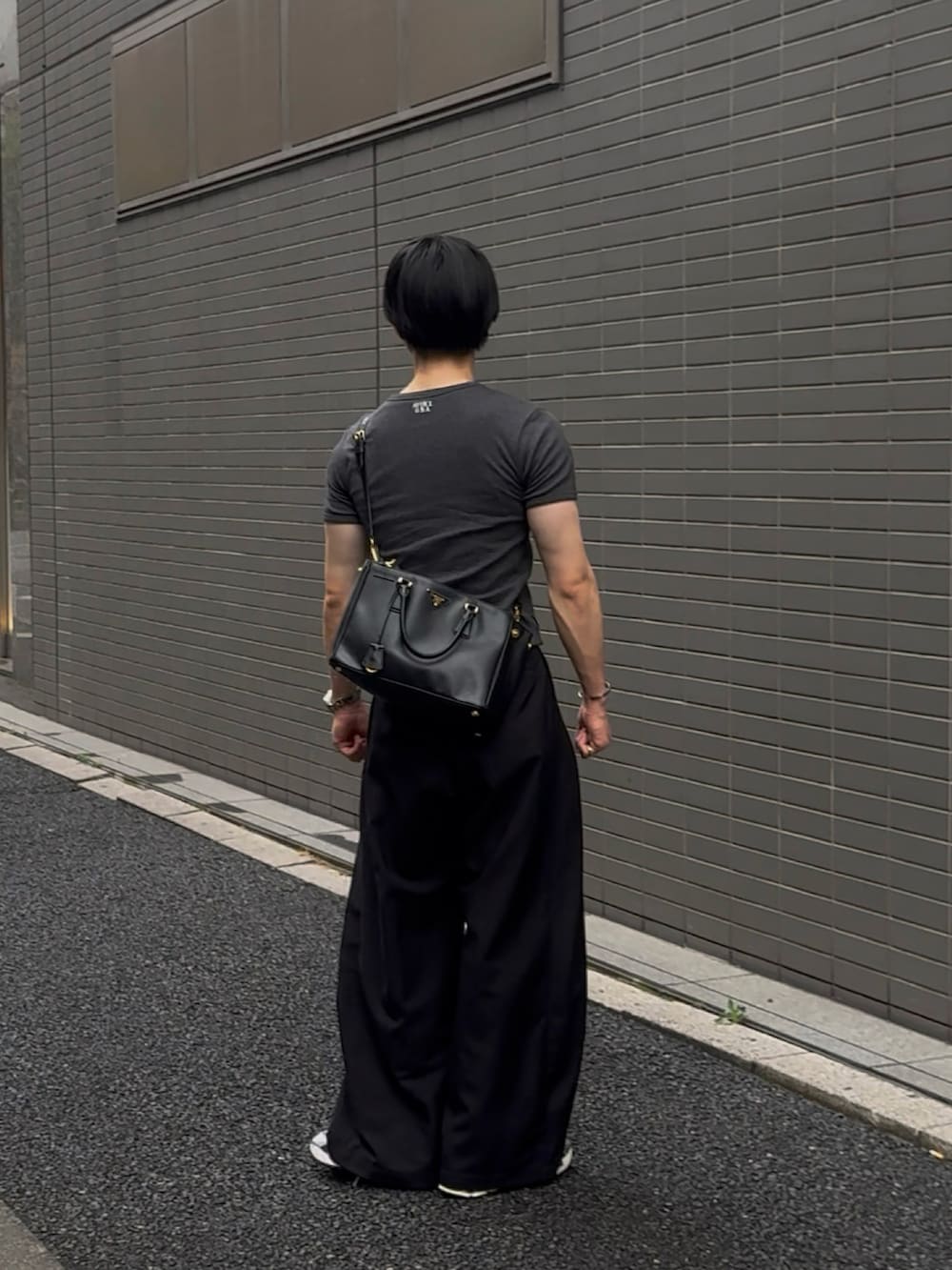 グレー系のTシャツ/カットソー、ブラック系のスラックス、グレー系のスニーカーを着用したメンズの夏コーディネートの2枚目の写真