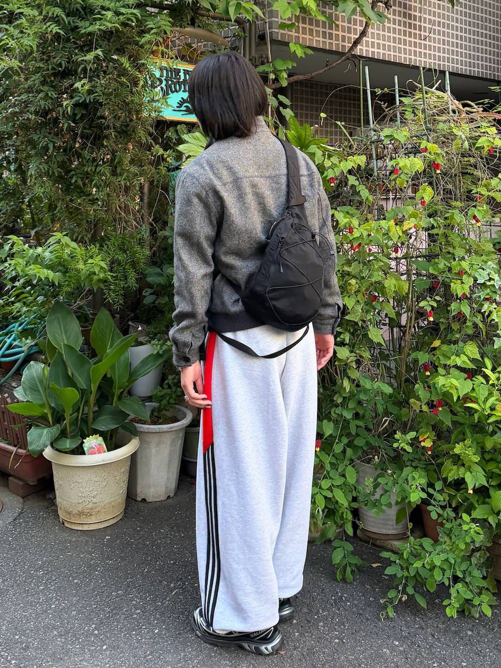 ブラック系のスニーカー、グレー系のパンツ、ブラック系のショルダーバッグを着用したメンズの春コーディネートの2枚目の写真