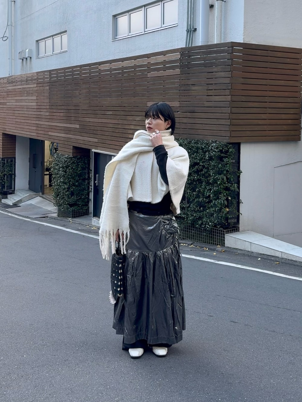 ブラック系のトートバッグ、シルバー系のスカート、ホワイト系のブーツを着用したメンズの冬コーディネートの3枚目の写真