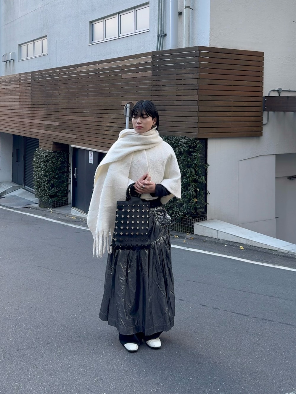ブラック系のトートバッグ、シルバー系のスカート、ホワイト系のブーツを着用したメンズの冬コーディネートの2枚目の写真