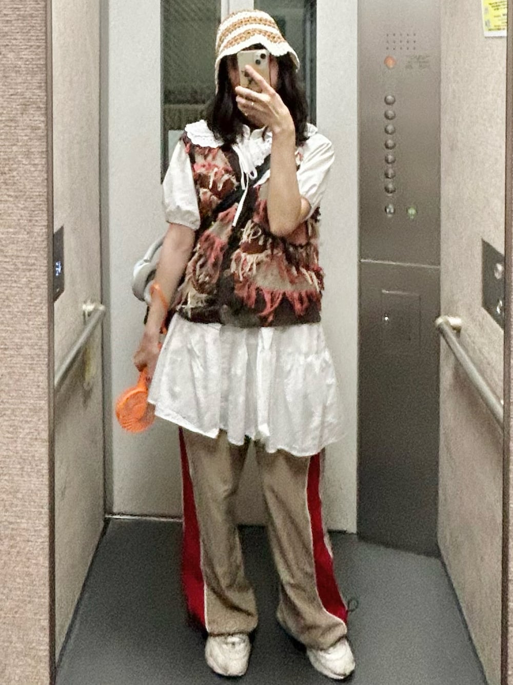 ブラウン系のベスト、ホワイト系のワンピース、ベージュ系のカーゴパンツを着用したレディースの夏コーディネートの2枚目の写真