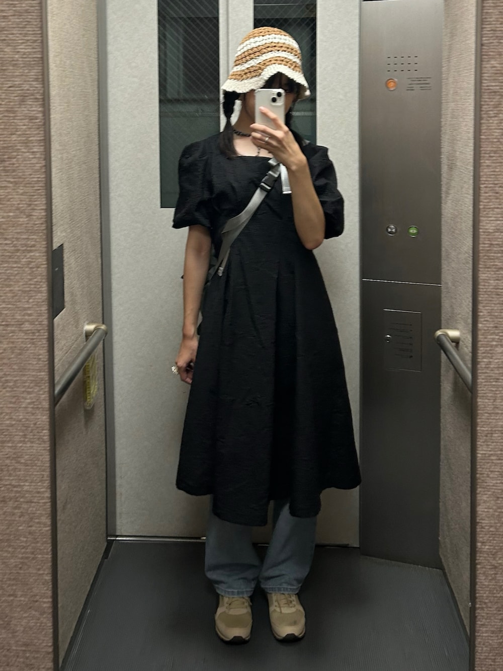 グレー系のショルダーバッグ、ベージュ系のスニーカー、ブラック系のワンピースを着用したレディースの秋コーディネートの2枚目の写真