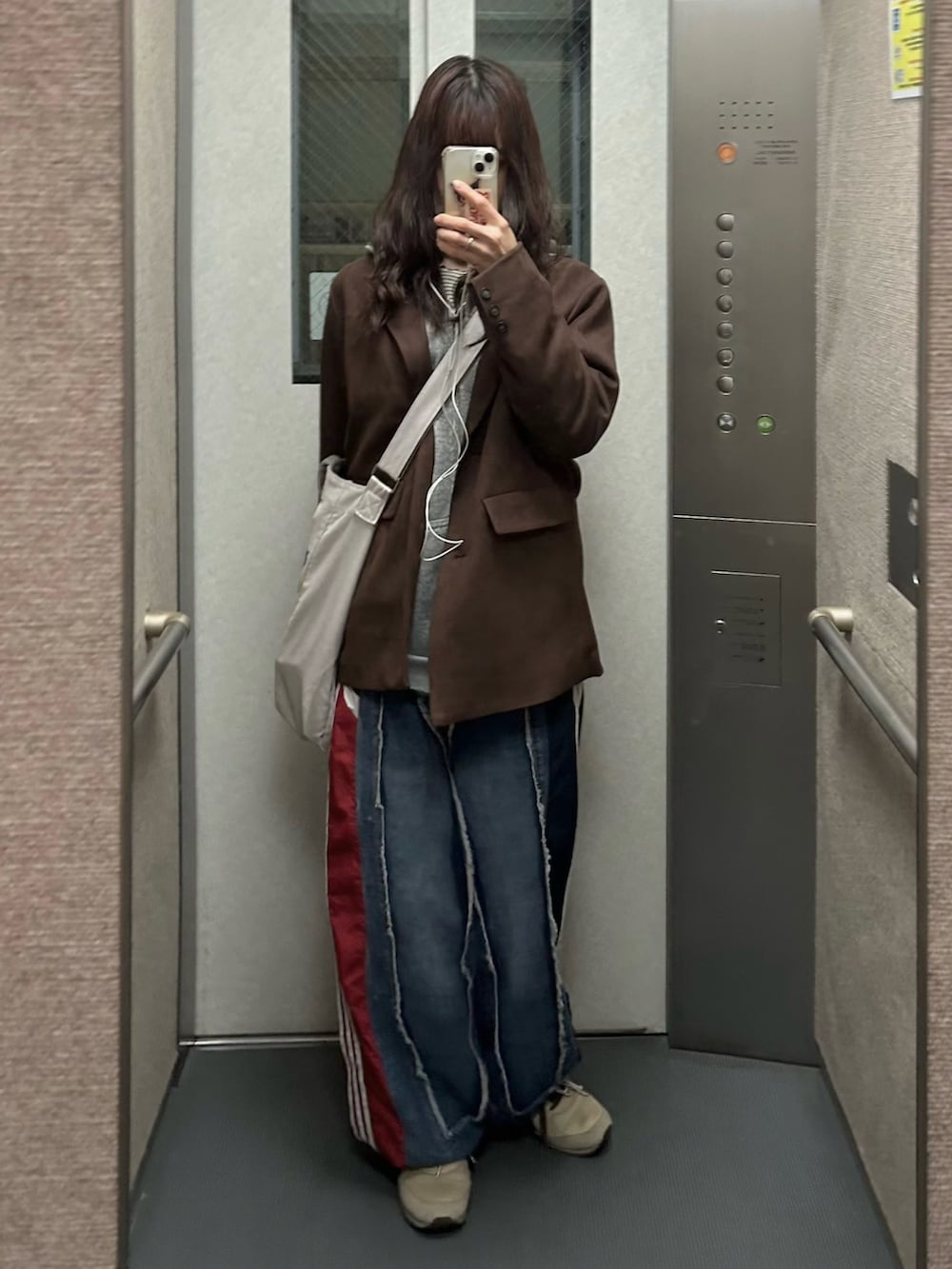 ブルー系のデニムパンツ、ブラウン系のテーラードジャケット、ピンク系のバッグを着用したレディースの冬コーディネートの2枚目の写真