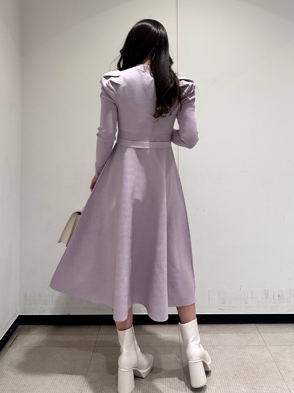 ホワイト系のハンドバッグ、パープル系のワンピース、ホワイト系のブーツを着用したレディースの冬コーディネートの3枚目の写真