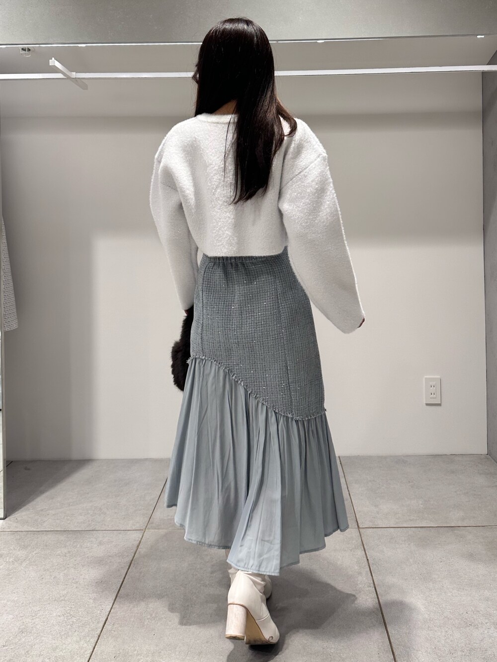 ホワイト系のカーディガン/ボレロ、ブラウン系のハンドバッグ、グリーン系のスカートを着用したレディースの秋コーディネートの3枚目の写真