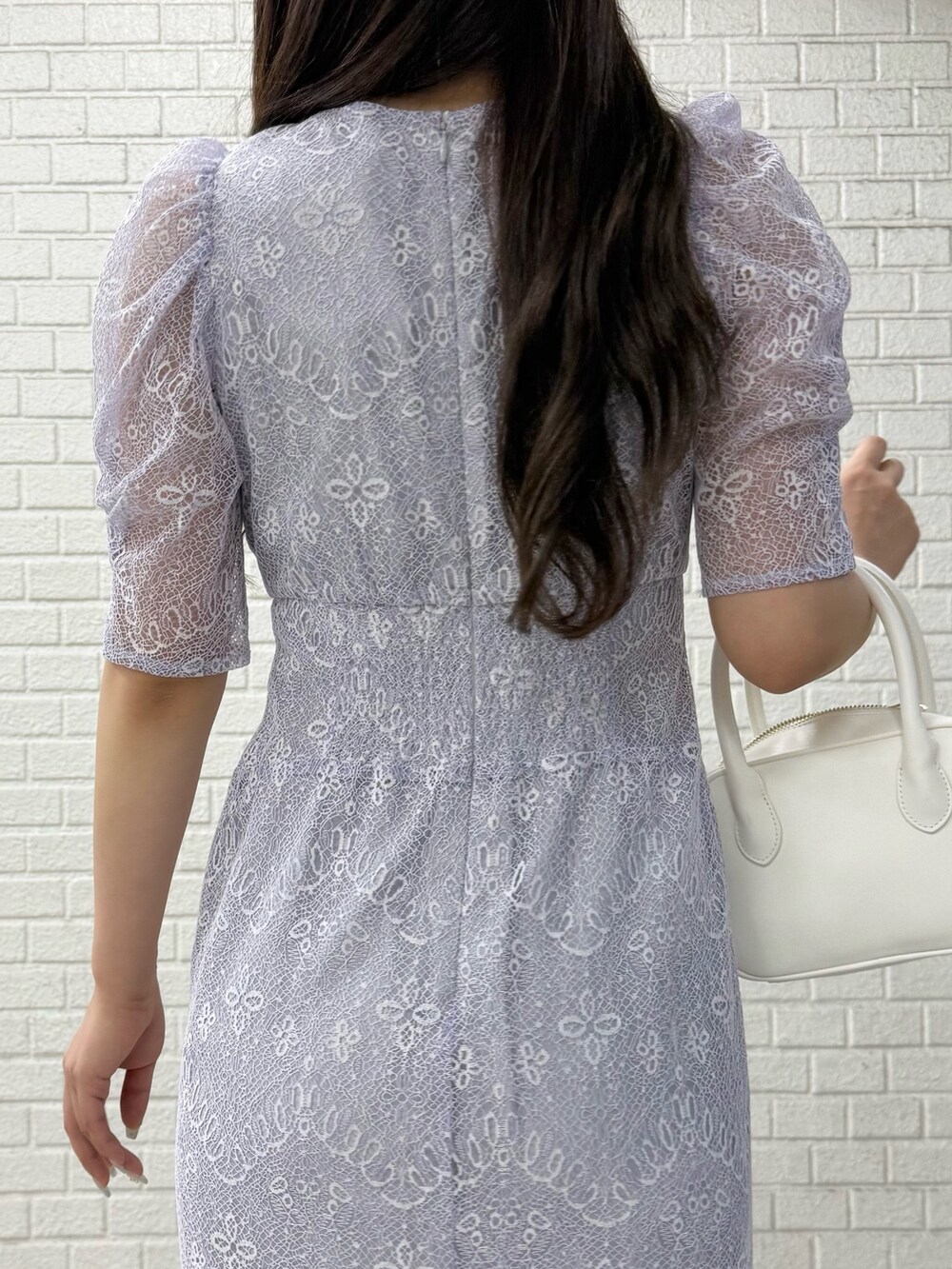 ベージュ系のパンプス、ホワイト系のハンドバッグ、パープル系のドレスを着用したレディースの秋コーディネートの6枚目の写真