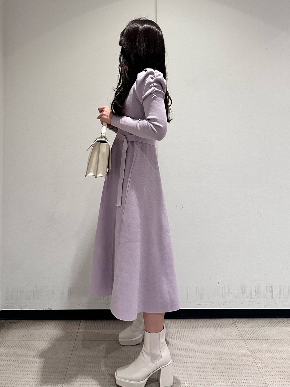 ホワイト系のハンドバッグ、パープル系のワンピース、ホワイト系のブーツを着用したレディースの冬コーディネートの2枚目の写真