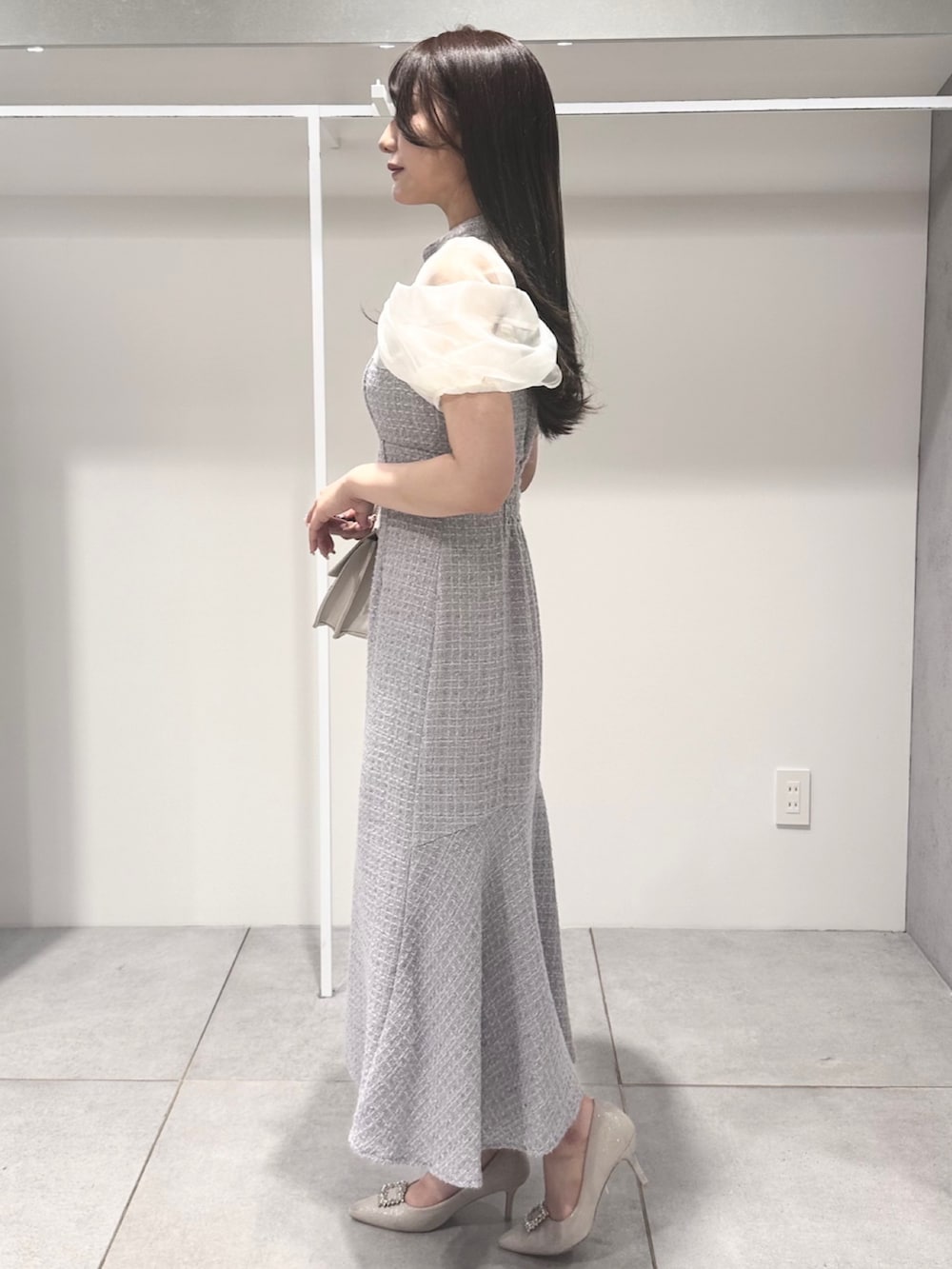 パープル系のワンピース、ホワイト系のパンプス、ベージュ系のショルダーバッグを着用したレディースの夏コーディネートの2枚目の写真