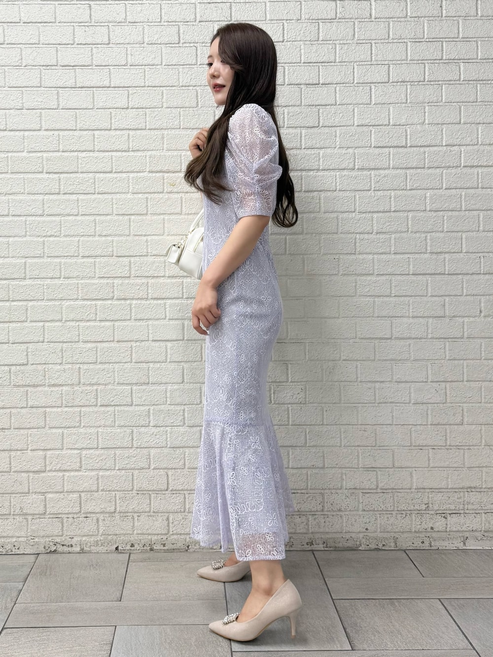 ベージュ系のパンプス、ホワイト系のハンドバッグ、パープル系のドレスを着用したレディースの秋コーディネートの2枚目の写真