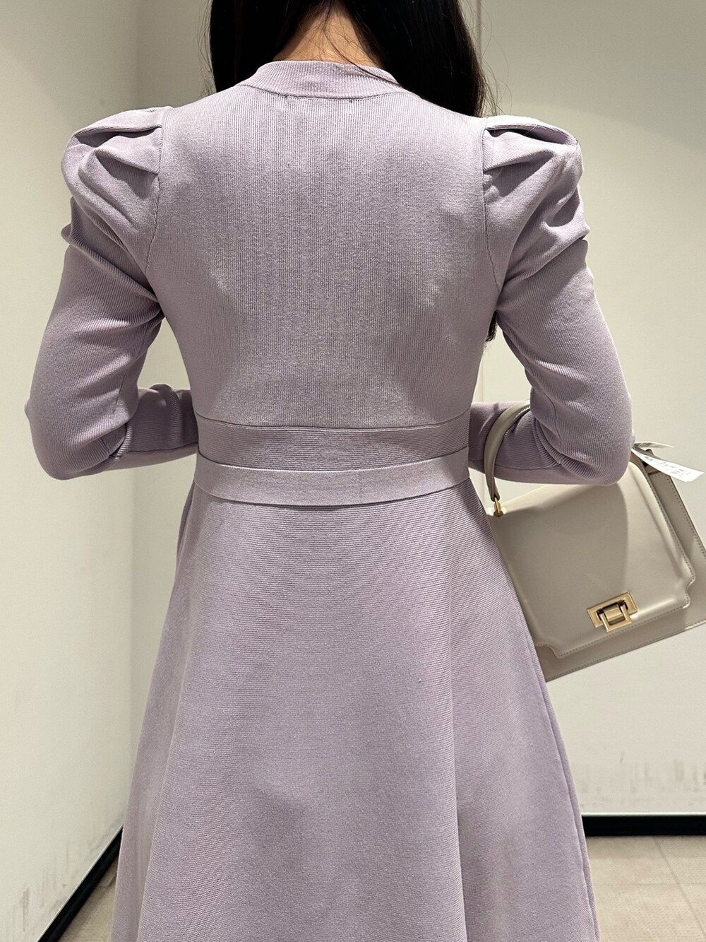 ホワイト系のハンドバッグ、パープル系のワンピース、ホワイト系のブーツを着用したレディースの冬コーディネートの6枚目の写真