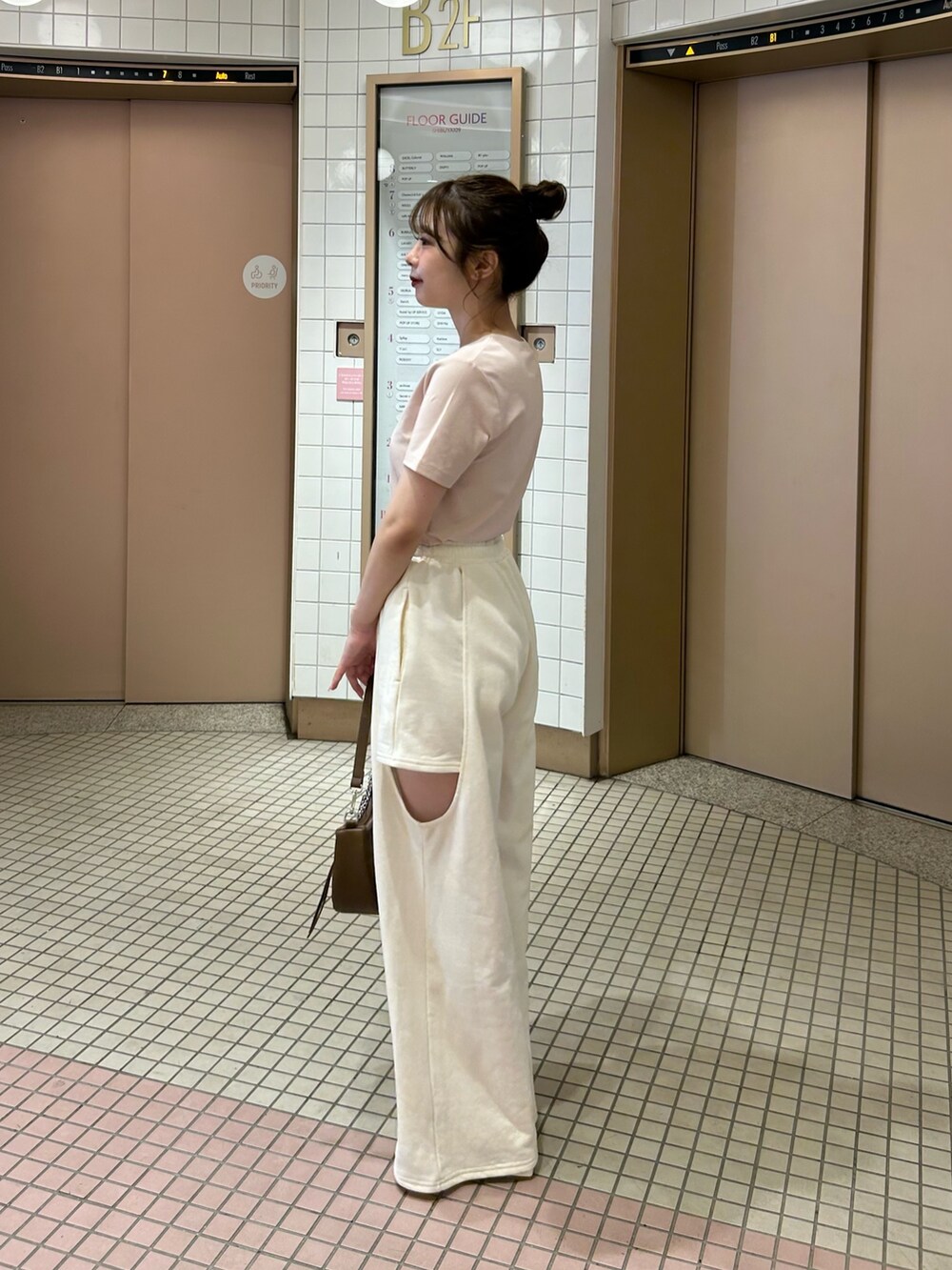 ホワイト系のパンツ、ピンク系のTシャツ/カットソー、ブラウン系のショルダーバッグを着用したレディースの春コーディネートの5枚目の写真