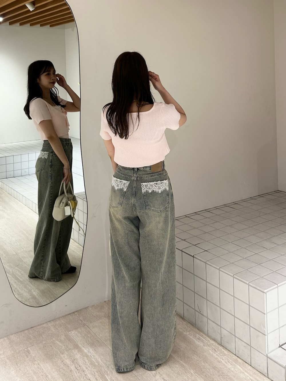 ブルー系のデニムパンツ、ホワイト系のボストンバッグ、ピンク系のカーディガン/ボレロを着用したレディースの夏コーディネートの6枚目の写真