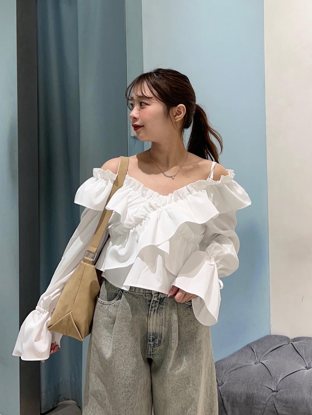 ブルー系のデニムパンツ、ホワイト系のシャツ/ブラウス、ベージュ系のショルダーバッグを着用したレディースの春コーディネートの2枚目の写真