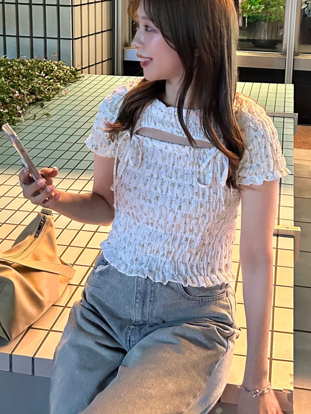 ブルー系のデニムパンツ、ホワイト系のTシャツ/カットソー、ベージュ系のショルダーバッグを着用したレディースの夏コーディネートの3枚目の写真
