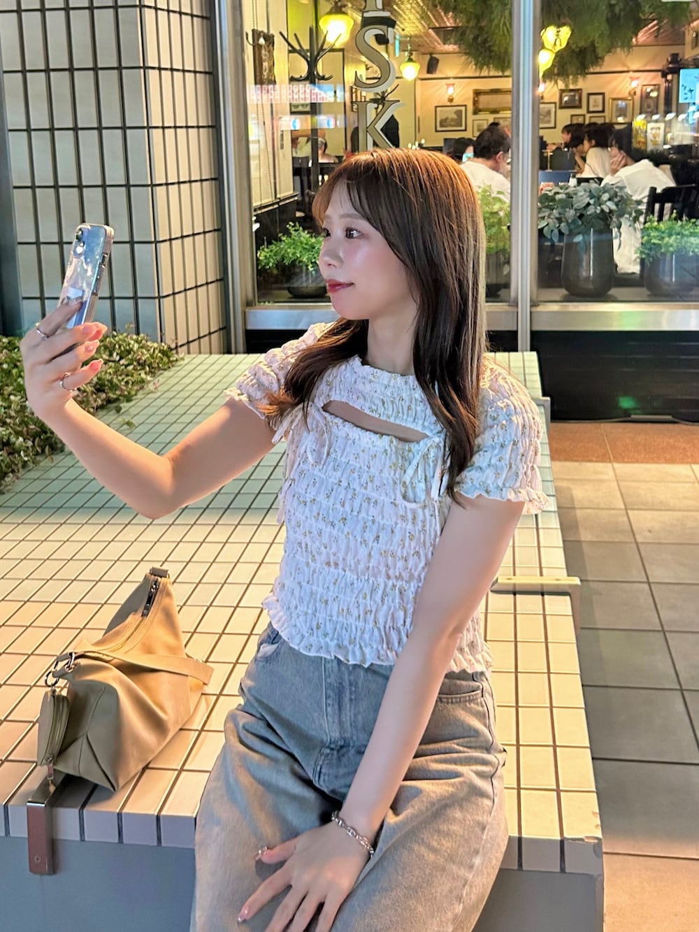 ブルー系のデニムパンツ、ホワイト系のTシャツ/カットソー、ベージュ系のショルダーバッグを着用したレディースの夏コーディネートの2枚目の写真