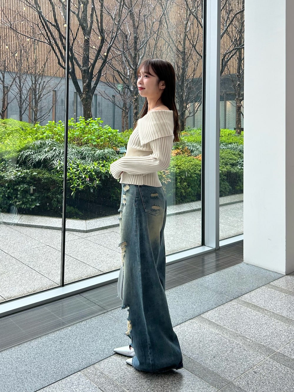 ホワイト系のニット/セーター、ブルー系のデニムパンツ、シルバー系のショルダーバッグを着用したレディースの春コーディネートの3枚目の写真