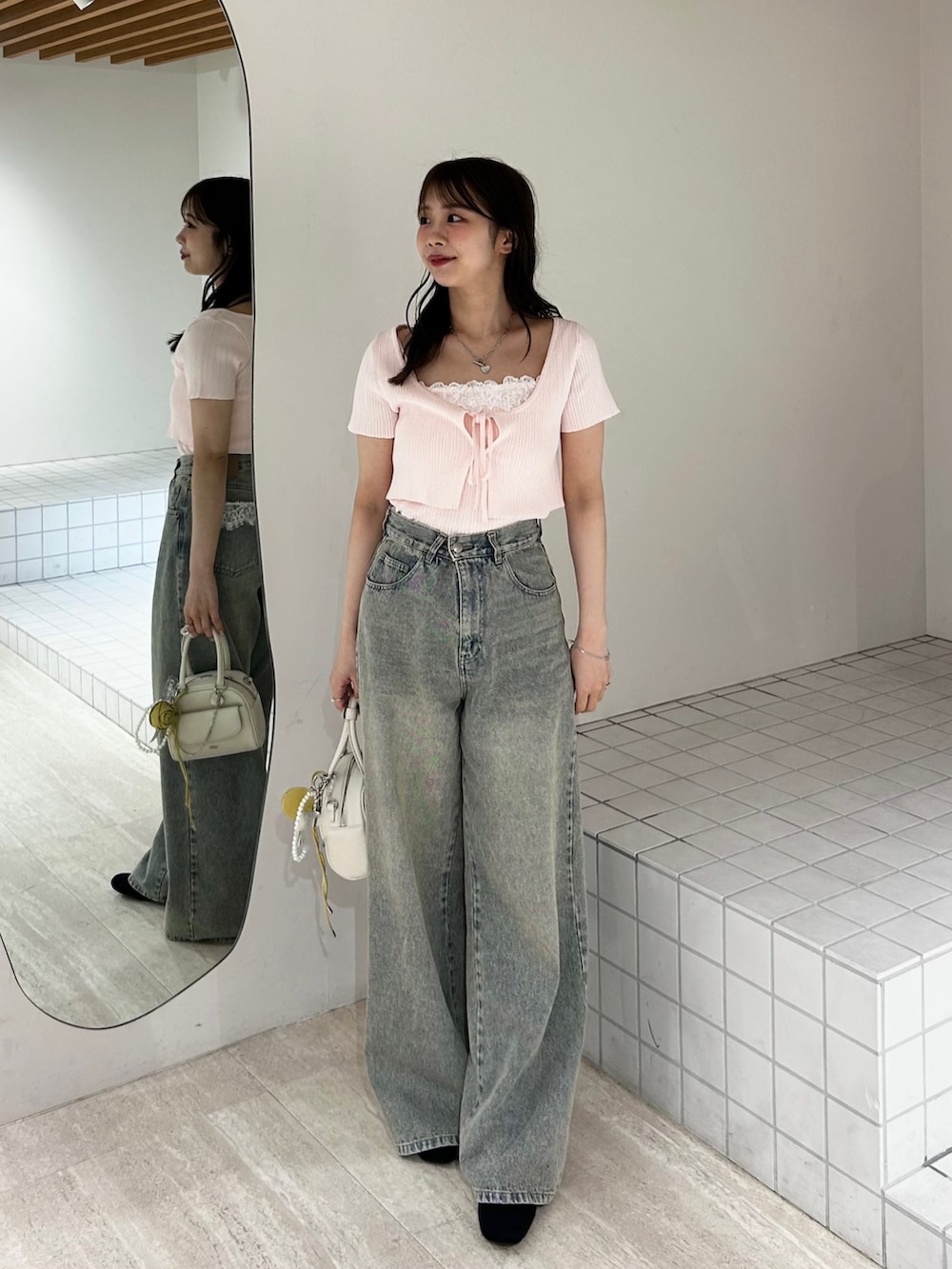 ブルー系のデニムパンツ、ホワイト系のボストンバッグ、ピンク系のカーディガン/ボレロを着用したレディースの夏コーディネートの3枚目の写真