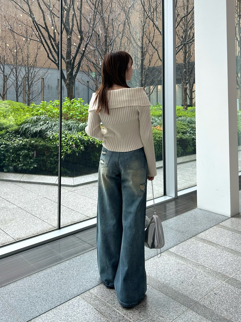 ホワイト系のニット/セーター、ブルー系のデニムパンツ、シルバー系のショルダーバッグを着用したレディースの春コーディネートの5枚目の写真