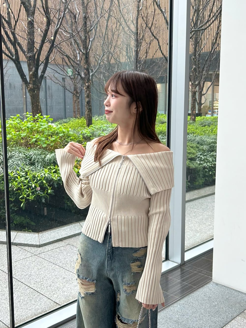 ホワイト系のニット/セーター、ブルー系のデニムパンツ、シルバー系のショルダーバッグを着用したレディースの春コーディネートの2枚目の写真